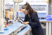 Operatrice che controlla smartphone in un laboratorio tecnico, attività tipica delle aziende che scelgono soluzioni di locazione operativa per dispositivi tecnologici