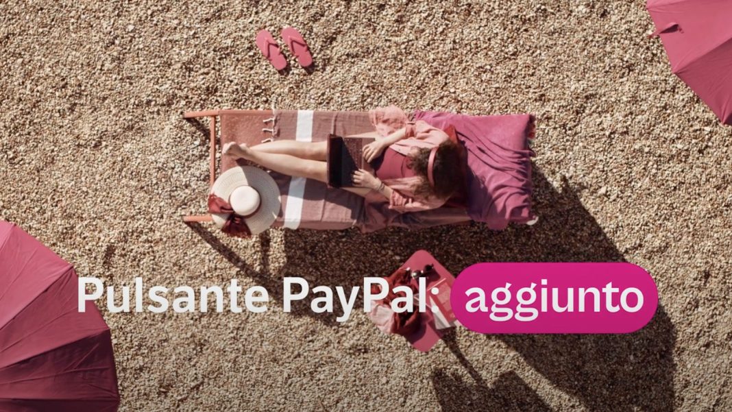 Donna al lavoro da remoto su una spiaggia con il testo “Pulsante PayPal aggiunto”, a rappresentare la semplicità e la flessibilità nei pagamenti digitali ovunque ci si trovi