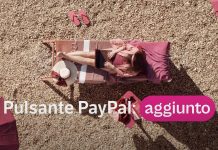 Pagamenti digitali: tutti i vantaggi per aziende e clienti Donna al lavoro da remoto su una spiaggia con il testo “Pulsante PayPal aggiunto”, a rappresentare la semplicità e la flessibilità nei pagamenti digitali ovunque ci si trovi