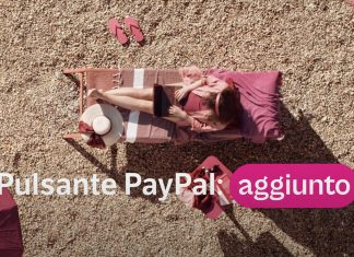 Donna al lavoro da remoto su una spiaggia con il testo “Pulsante PayPal aggiunto”, a rappresentare la semplicità e la flessibilità nei pagamenti digitali ovunque ci si trovi