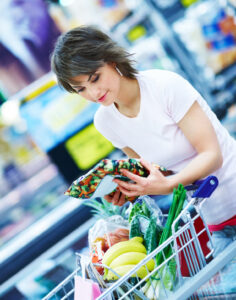 Portrait of a happy young woman with her purchased grocery items in a cart