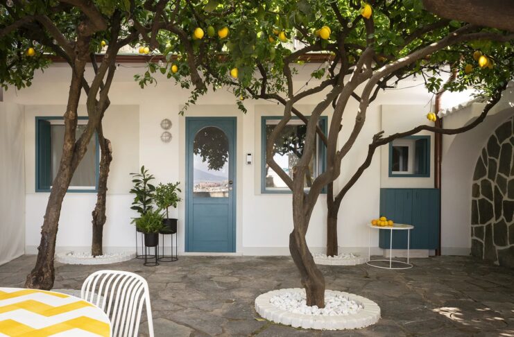 Le finestre blu e la porta della mini casa a Posillipo si affaccia sul patio panoramico con alberi di limoni