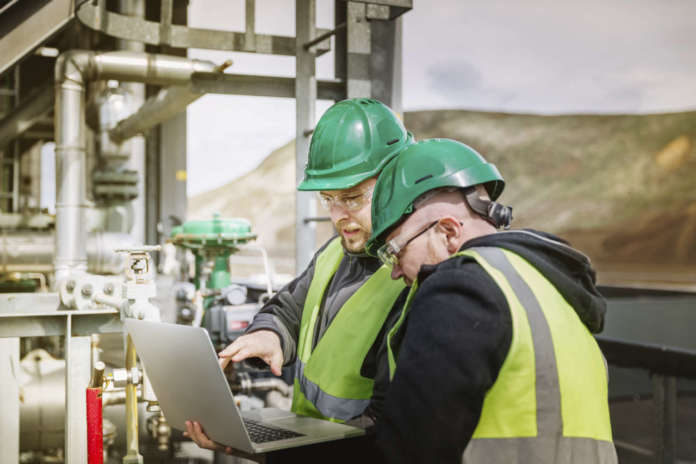 Professional experts discussing over laptop at factory Le tecnologie per Rspp e Hse