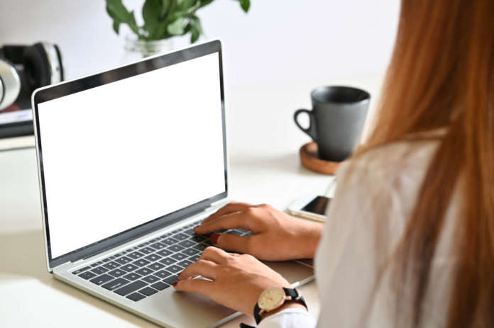 Young woman using mockup laptop computer on table. Bando Isi: download prorogato