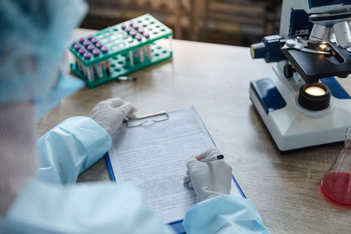 The doctor conducts research in the laboratory. Writes information to a document. Privacy: le deroghe nella ricerca medica