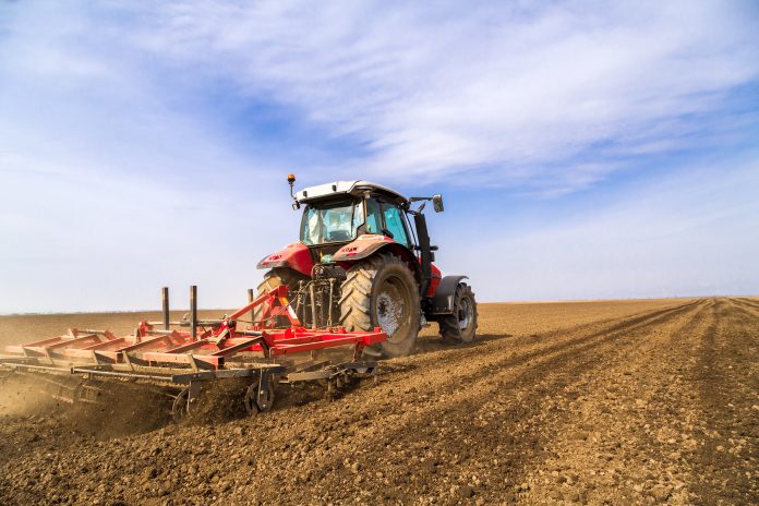 Farmer in tractor preparing land with seedbed cultivator Riduzione dei contributi Inail per l'agricoltura: