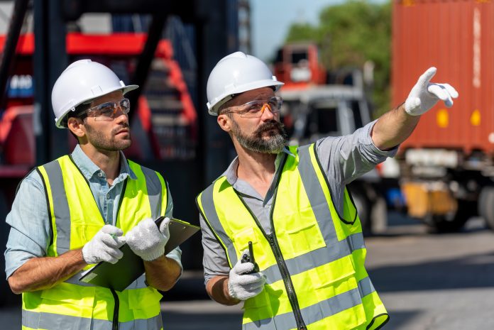 Logistics engineer and inspector working togetter and discussing in shipping containerin commercial transport port Il Dl sicurezza è legge