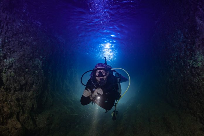 A male scuba diver in the ocean at night. The shot is backlit to create an interesting effect Sicurezza delle attività subacquee