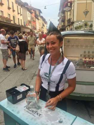 Una sorridente hostess ha offerto una degustazione pubblica di Kranebet davanti all'Hotel Croce Bianca in corso 4 novembre ad Asiago