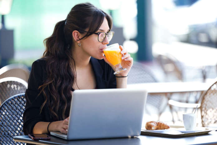 Shot,Of,Beautiful,Young,Woman,Drinking,Orange,Juice,While,Working