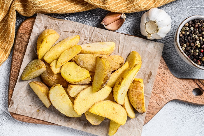 Frozen potato wedges on a cutting board. Recipe for French Fries. White background. Top view