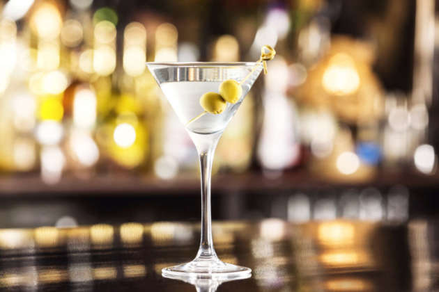 Closeup glass of martini dry cocktail with olives at bar counter