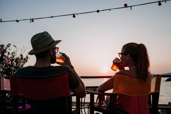 Young,Couple,Enjoying,Beer,And,Sunset,In,A,Beach,Bar