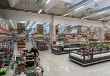 Cash & Carry: come scegliere il partner strategico per i bar nel 2025 Interno di un cash & carry per bar con ampi scaffali, prodotti food & beverage e un operatore Horeca che rifornisce il carrello