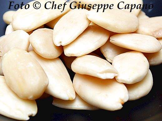 Le mandorle e una crema dolce leggera per il panettone Mandorle sgusciate e pelate sfondo nero 518