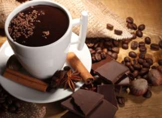 La cioccolata diventa veg cup of hot chocolate, cinnamon sticks, nuts and chocolate on wooden table