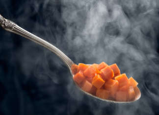 cucchiaio che contiene cubetti di carota cotti con la cucina a vapore
