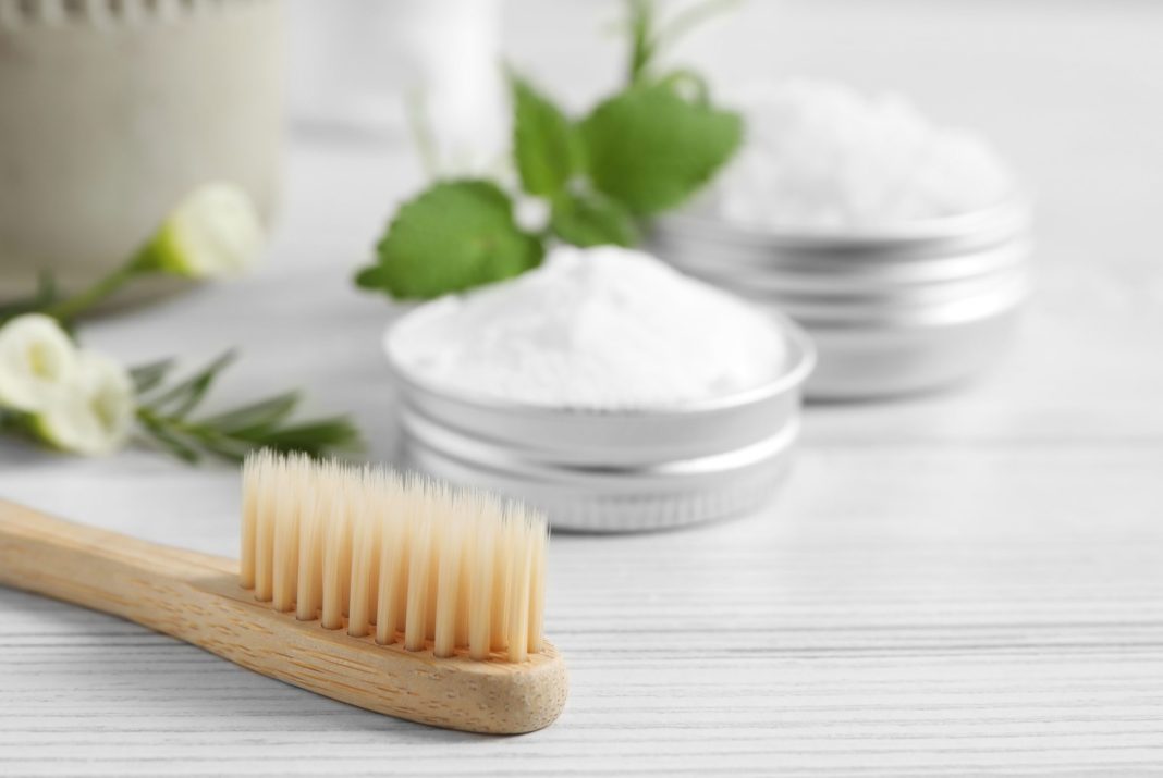 Toothbrush, dental products and herbs on white wooden table, closeup. Space for text