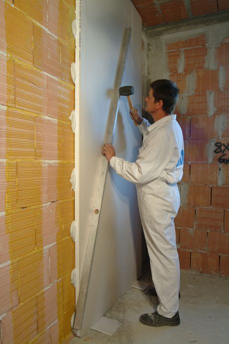 Le lastre a parete sono battute manualmente o con regolo metallico per l’allineamento con le tracce, accostando i pannelli adiacenti per evitare la fuoriuscita di adesivo e la formazione di ponti termici/acustici. A presa avvenuta si rimuovono gli spessori a terra e si procede alla stuccatura.