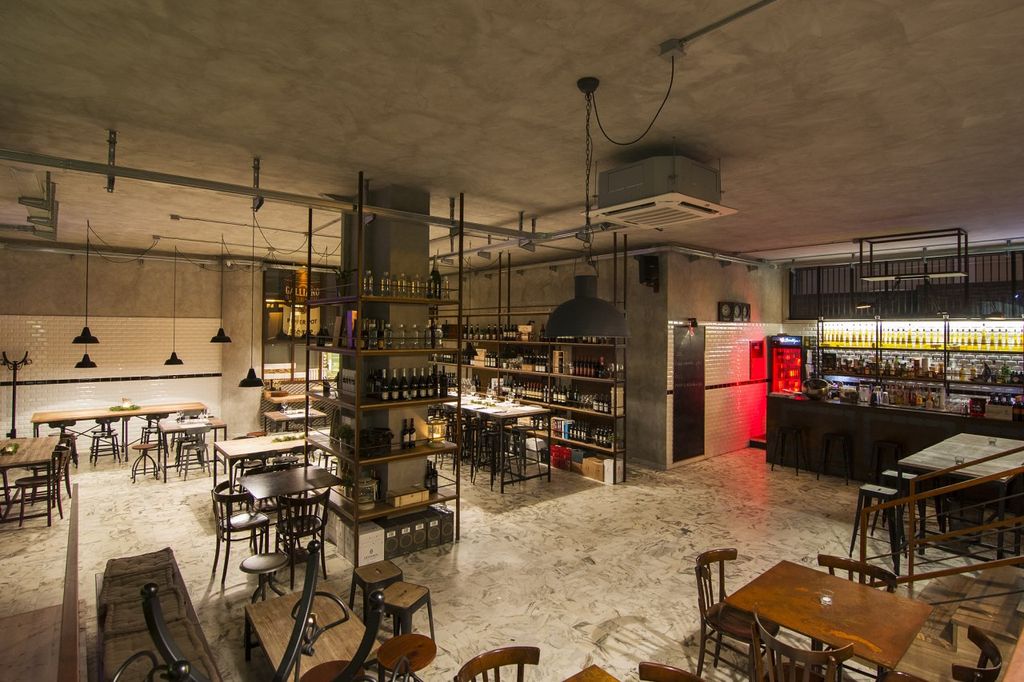 La sala principale arredata con tavoli e sgabelli in stile vintage. Sulla sinistra una parete rivestita con ceramica diamantata, smaltata bianca, di gusto molto retrò