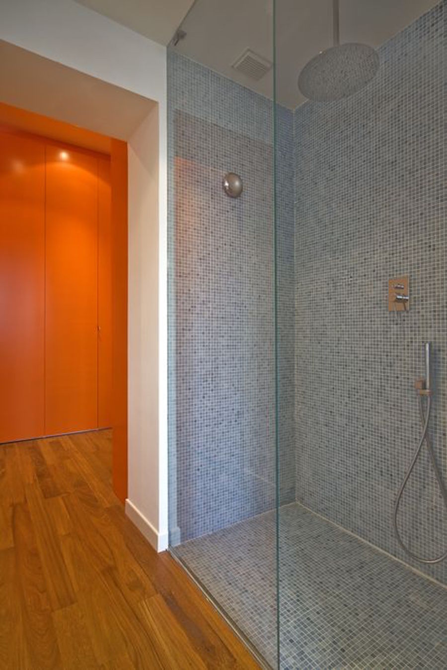La doccia, rivestita con piastrelle in mosaico, è a filo pavimento e schermata solo da un pannello in cristallo trasparente (foto Beppe Giardino)