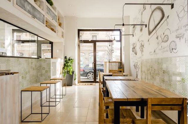 L’ingresso del Bis Panzerotti si affaccia sulla strada, con un serramento in metallo scuro che occupa quasi l’intera parete. Una finestratura a nastro mantiene la comunicazione tra il locale consumazione e la cucina (foto di Gregory Abbate)