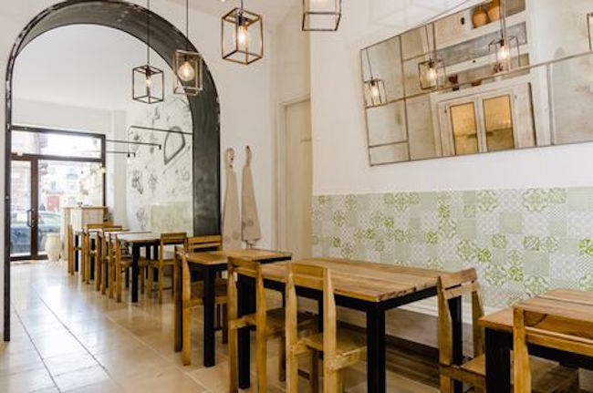 I due locali destinati al ristorante sono comunicanti ma separati da un’apertura ad arco, vincolo di un muro portante originale. Il pavimento è rivestito di pietra di Cave Tinella, largamente usata nell’architettura pugliese. Le lampade in metallo sono realizzate artigianalmente da Bernardo Palazzo (foto di Gregory Abbate)