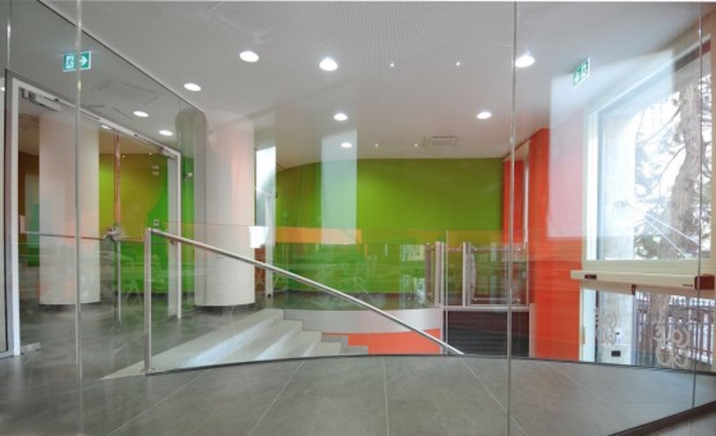 Vista dell’ingresso dall’emeroteca: gli spazi collettivi sono separati da pareti e vetrate, piane e curve (foto Luca Moretto)