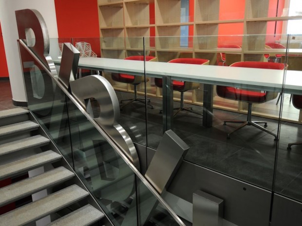 Scorcio della biblioteca, con la scritta che affianca la scala diretta al sottostante deposito dei libri (foto Luca Moretto)