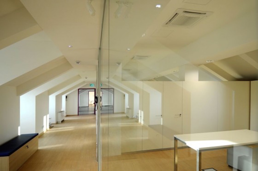 Gli uffici ottenuti grazie al recupero del sottotetto sono separati da pareti vetrate a tutta altezza (foto Luca Moretto)