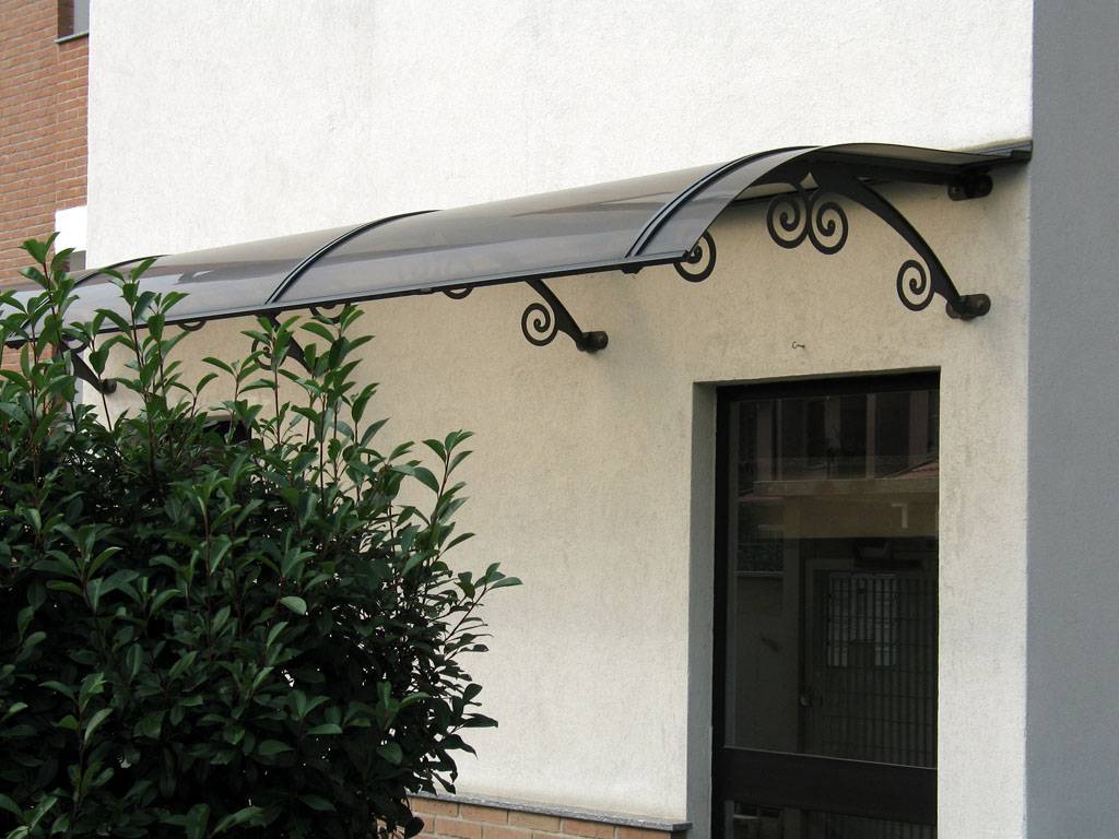 Angelica. Soluzione classica ed elegante, è una pensilina autoportante realizzata con archi in acciaio e profili estrusi in alluminio e completa di lastra in policarbonato compatto con protezione Uv. La misura a sbalzo unico è di 1250 mm (foto Polypiù)