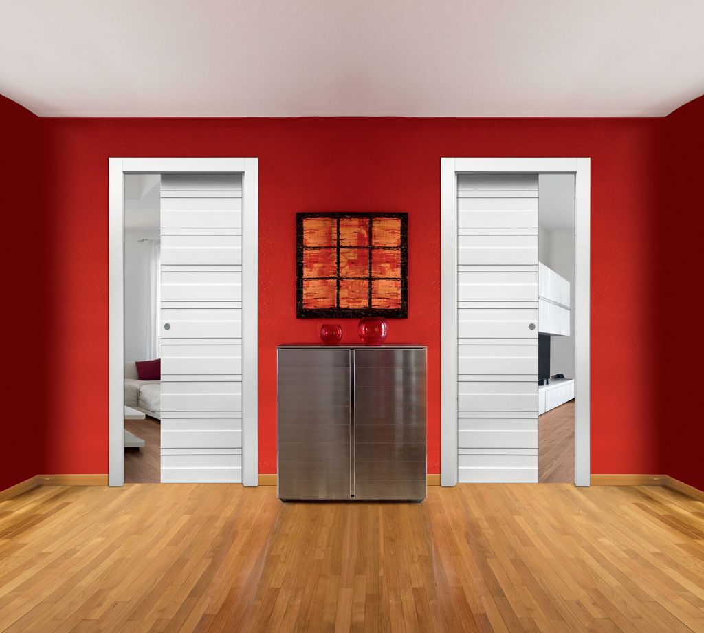 Space Duetto con porte interne laccate bianco neve con doghe orizzontali. La guida in acciaio garantisce lo scorrimento fluido e silenzioso dell’anta ed è comunque estraibile anche a installazione terminata. Può quindi essere sostituita senza lavori di muratura o altri interventi onerosi (foto Dierre)