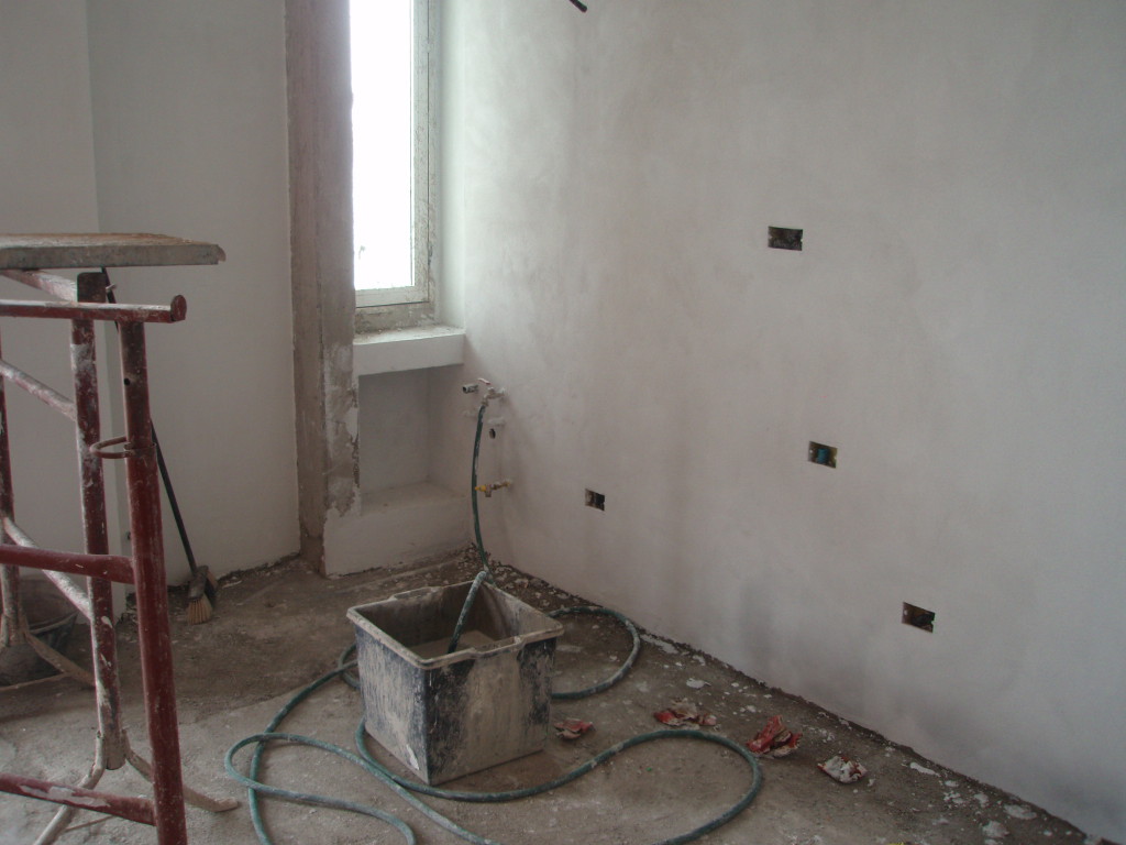 Rasatura a gesso su intonaco rustico di fondo.