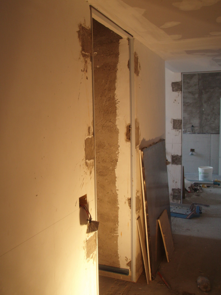 Posa di telai rasomuro in alluminio per porte a battente.