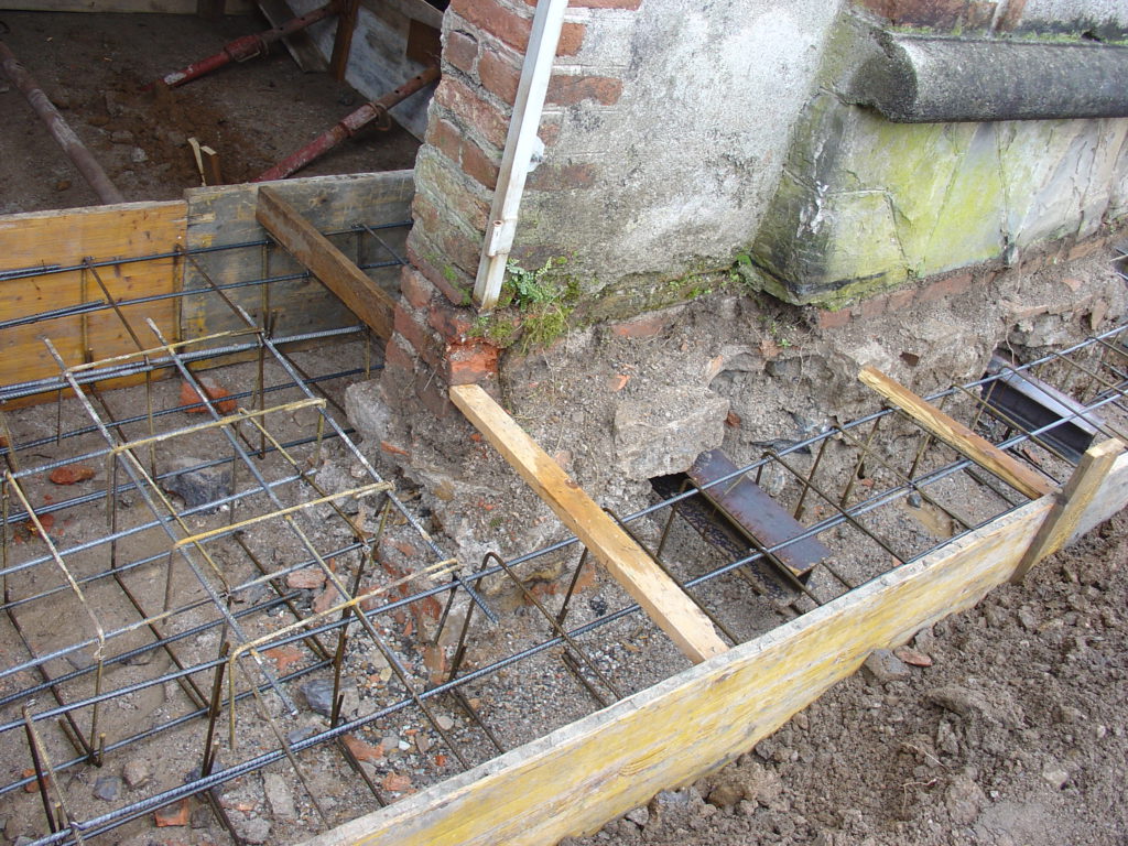 Villa Amalia | Rinforzo della fondazione tramite la realizzazione di cordoli ai fianchi del muro e con connessione tramite profili in acciaio delle cordonature.