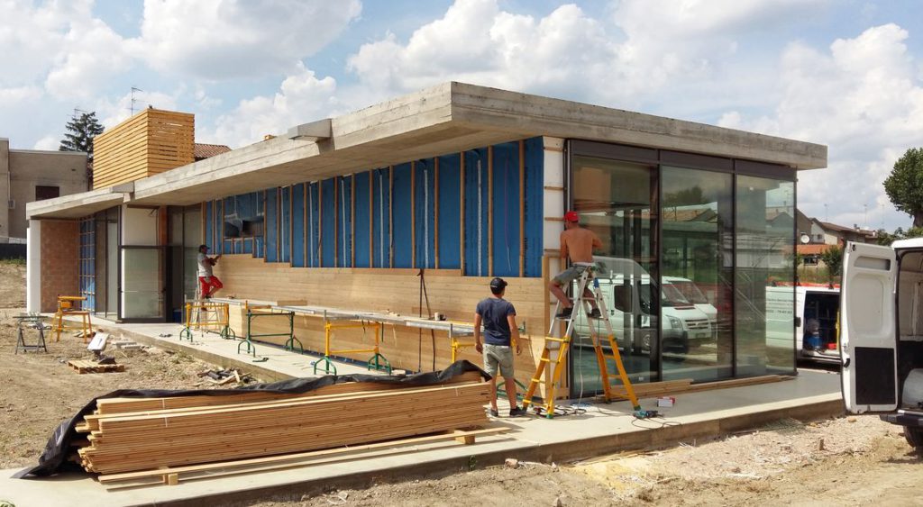 Fase di avvitamento delle doghe di legno di larice siberiano su montanti in legno tassellati a muro.