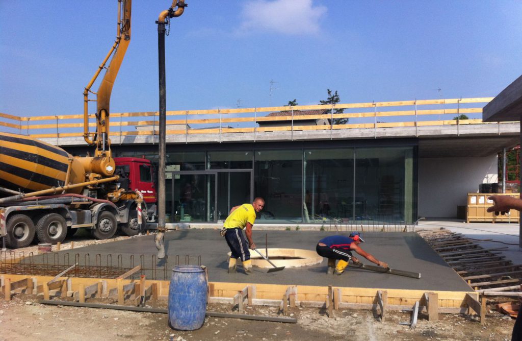 Getto della pedana in cemento esterna con ferri di ripresa per panche e cassero circolare per foro di alloggiamento della quercia.