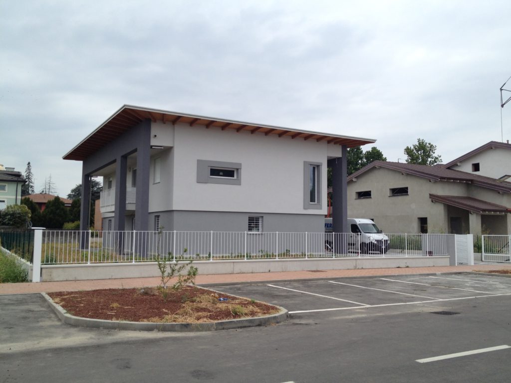 Vista frontale e laterale della villa e il cornicione in legno lamellare a compluvio che caratterizza la casa.