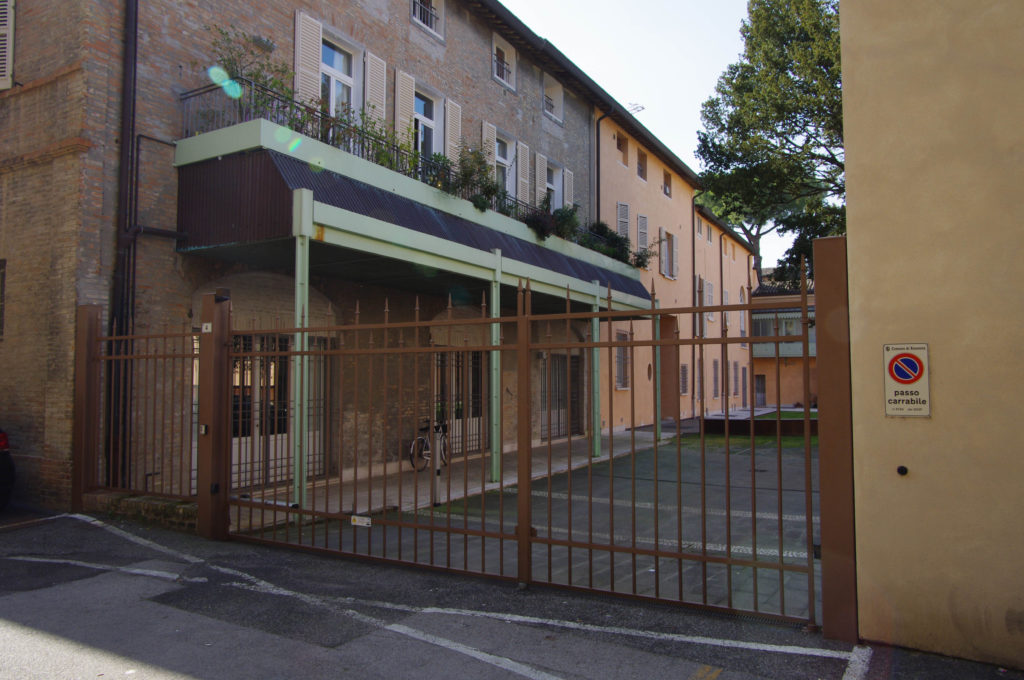 Fronte interno da via Pier Traversari, ingresso auto e pedonale, con pensilìna in ferro di nuova esecuzione agganciata alla parete e alla terrazza esistente che ospita gli impianti di climatizzazione.