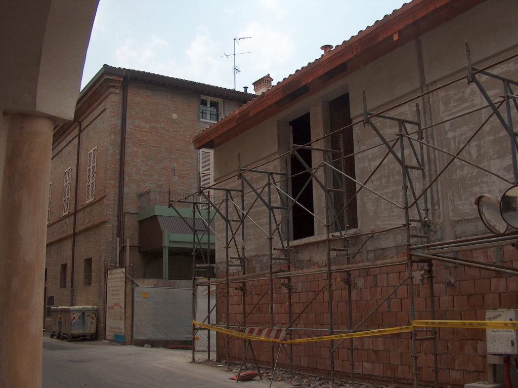 Edificio di nuova costruzione sul fronte di via Pier Traversari con a fianco dettaglio dell’abside di S. Maria Maggiore e particolare della bifora in costruzione.