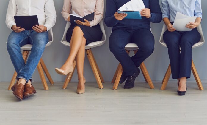 Group of job seekers sitting on chairs in row with resumes and waiting in line for interview