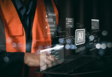 Tecnico con gilet di sicurezza che utilizza un laptop con interfacce di intelligenza artificiale per l'automazione dei processi amministrativi e la riconciliazione bancaria