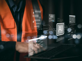 Tecnico con gilet di sicurezza che utilizza un laptop con interfacce di intelligenza artificiale per l'automazione dei processi amministrativi e la riconciliazione bancaria