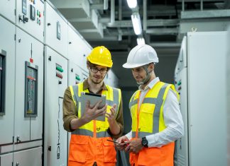 Tecnici elettrici in cantiere consultano un tablet per la gestione amministrativa degli impianti elettrici con software in cloud