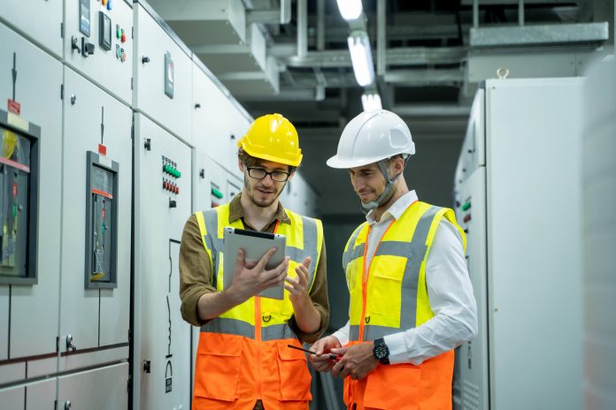 Gestione amministrativa impianti elettrici AdobeStock_422504615 Tecnici elettrici in cantiere consultano un tablet per la gestione amministrativa degli impianti elettrici con software in cloud