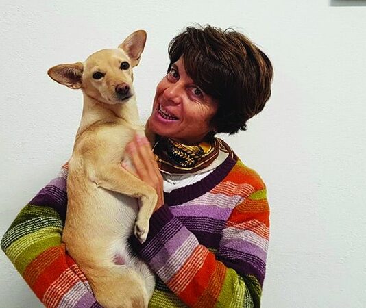 Benessere del cane: comprendere comportamento, alimentazione e integrazione Sabrina Giussani, Medico Veterinario Esperto in Comportamento Animale, tiene in braccio un cane, mostrando attenzione e cura.