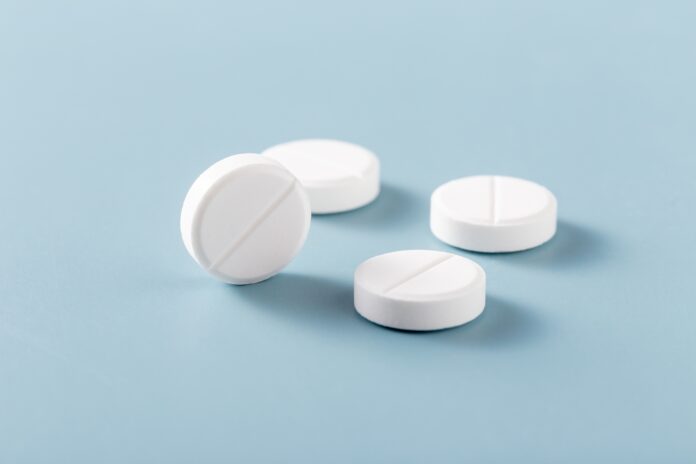 White,Pills,With,Glass,On,Blue,Background
