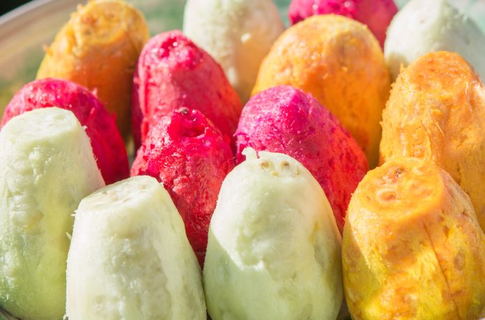 Ficodindia dell’Etna DOP di diverse varietà (gialla, rossa e bianca) sbucciati, esposti in primo piano, con sfondo sfocato dei frutti vulcanici di O.P. La Deliziosa