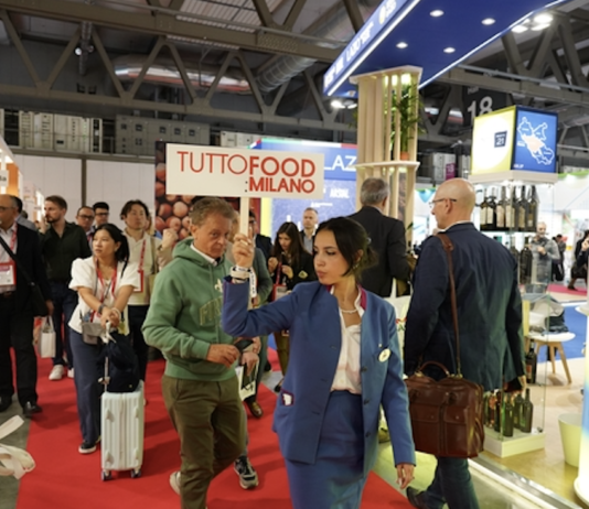 È “veg revolution”: TUTTOFOOD esplora le soluzioni vegetali evolute e premia i reparti europei del fresco Interno dei padiglioni di TUTTOFOOD 2026 a Rho Fieramilano con visitatori tra gli stand e hostess che sorregge il cartello ufficiale della manifestazione