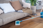 Superduster: nuovo catturapolvere ecologico per superfici e pavimenti Superduster Leifheit in azione mentre pulisce sotto un divano, ideale per la rimozione della polvere su pavimenti in legno in modo sostenibile